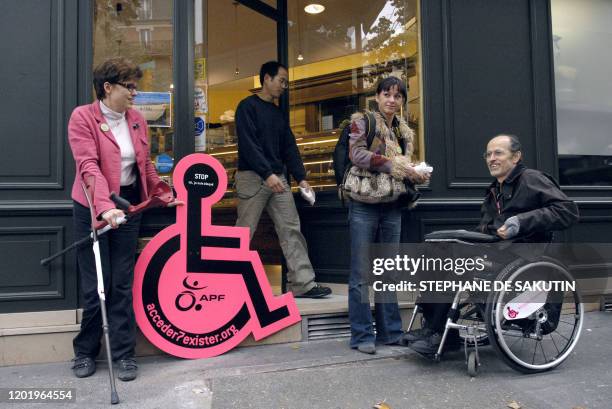 Une personne remet des croissants a un handicapé en fauteuil roulant, qui n'a pas eu accès à la boulangerie le 08 octobre 2007 à Paris. Une...