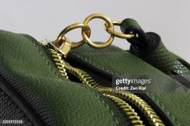 green handbag with unzipped gold colored zipper with three metal rings attached - luxury handbag stock pictures, royalty-free photos & images