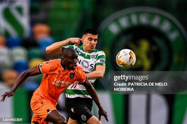 Sporting's Argentine midfielder Rodrigo Battaglia challenges Basaksehir's Senegalese forward Demba Ba during the Europa League round of 32 football...