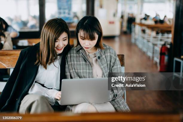 two asian young businesswomen using laptop and discussing a project while riding on a ferry - commuter ferry stock pictures, royalty-free photos & images