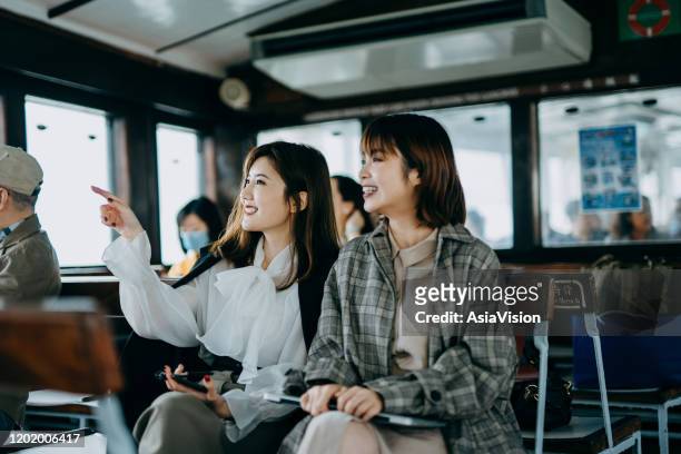兩個微笑的年輕亞洲婦女坐在一起，享受渡輪乘坐星輪 - ferry 個照片及圖片檔