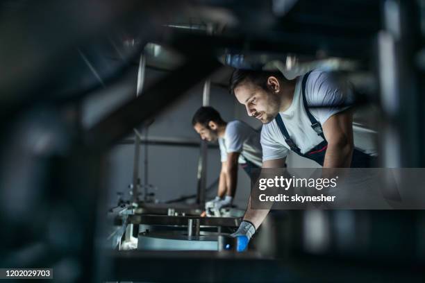 handarbeiders die aan een machine in een fabriek werken. - werktuigbouwkunde stockfoto's en -beelden