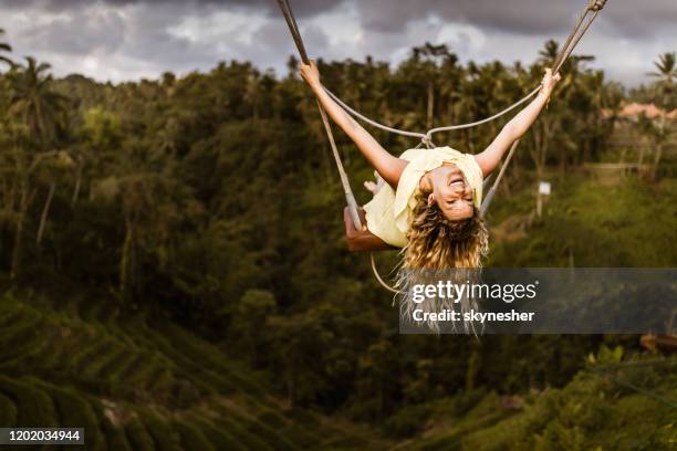 junge glückliche frau genießt, während sie über dem regenwald schwingt. - schaukel stock-fotos und bilder