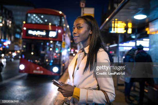 woman at bus stop in the night in london - bus stop uk stock pictures, royalty-free photos & images