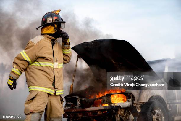 firefighter standing in front of a burned car - fire station - fotografias e filmes do acervo