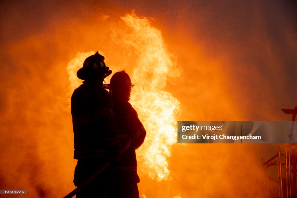 Silhouette of two firefighter in front of the big fire, Fire insurance concept