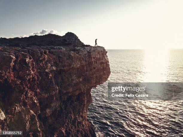 a tiny young man at the edge of a cliff - malta wandern stock-fotos und bilder