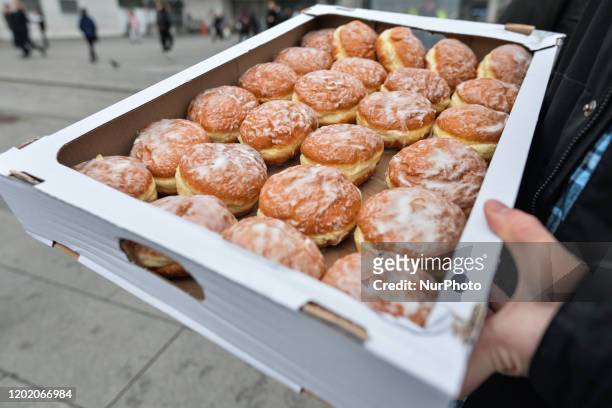 Man carries a box of Polish doughnuts on Fat Thursday in Krakow. Every February, Poland and Poles 'go nuts' for doughnuts on Fat Thursday, the last...