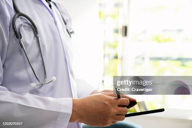 doctor is working with digital tablet at office in hospital. - krankenakte stock-fotos und bilder