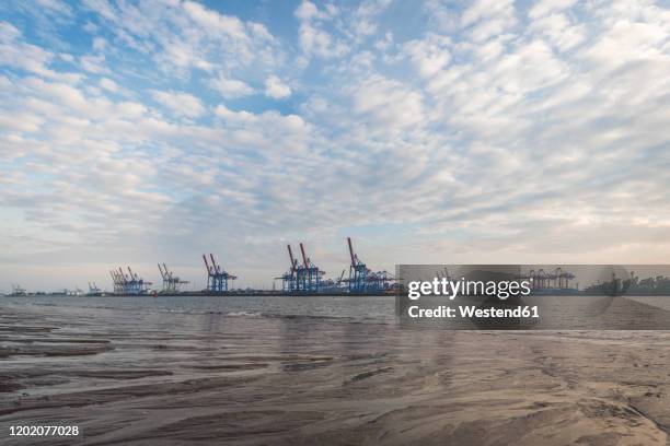 germany, hamburg, clouds over elbe river with harbor cranes in background - elbe stock-fotos und bilder