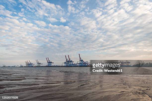 germany, hamburg, clouds over elbe river with harbor cranes in background - elbe river stock pictures, royalty-free photos & images