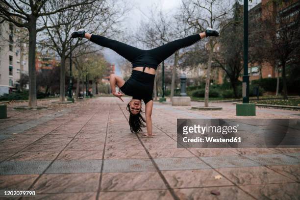 young woman in black sportswear doing handstand on one hand - slide tackle foto e immagini stock