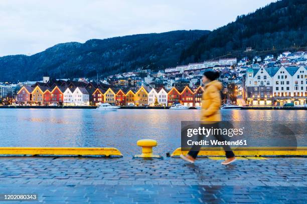 woman wearing a yellow jacket and walking at harbour in bergen, norway - bergen bildbanksfoton och bilder