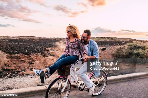 smiling couple on bicycle, tenerife, spain - ironia imagens e fotografias de stock