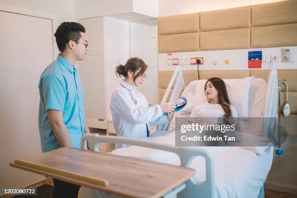 an asian chinese patient lying down on her bed in hospital ward listening to the female doctor's advise - patient lying down stock pictures, royalty-free photos & images