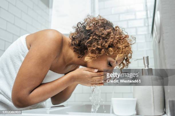 young woman at bathroom sink - washing face stock pictures, royalty-free photos & images