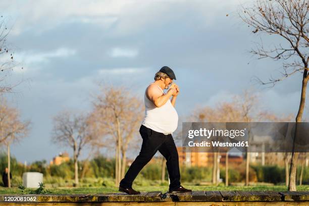 man with beer belly eating a sandwich - bierbauch stock-fotos und bilder