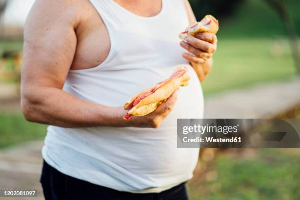 man with beer belly holding sandwich - bites stockfoto's en -beelden