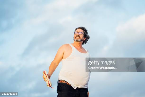 man with beer belly holding sandwich - sausage sandwich stock pictures, royalty-free photos & images