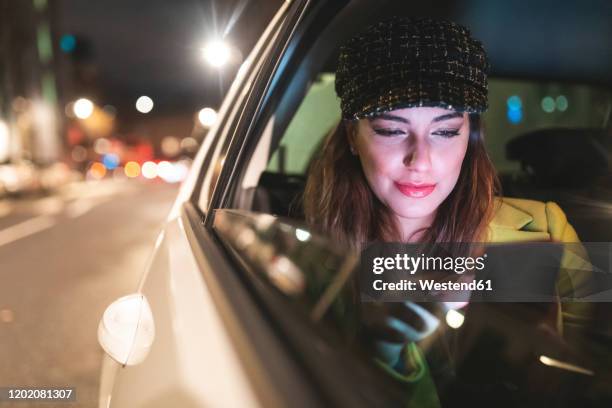 woman sitting on the backseat of a car in the city at night - london taxi stock pictures, royalty-free photos & images