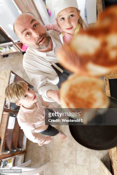 father and daughter cooking in the kitchen, turning pancakes in the air - pancake toss stock-fotos und bilder