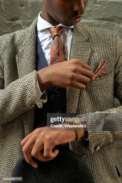 stylish businessman holding a beret and checking his pocket square - lapel 個照片及圖片檔