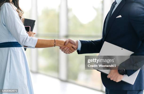 close-up of businessman and businesswoman shaking hands - social grace stock pictures, royalty-free photos & images