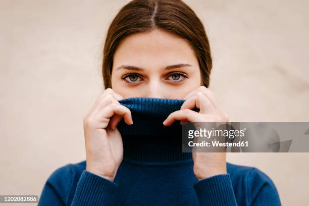 close up portrait of woman with blue turtleneck pullover - shy stockfoto's en -beelden