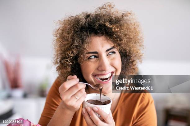 portrait of happy woman eating chocolate spread at home - chocolate spread stock pictures, royalty-free photos & images