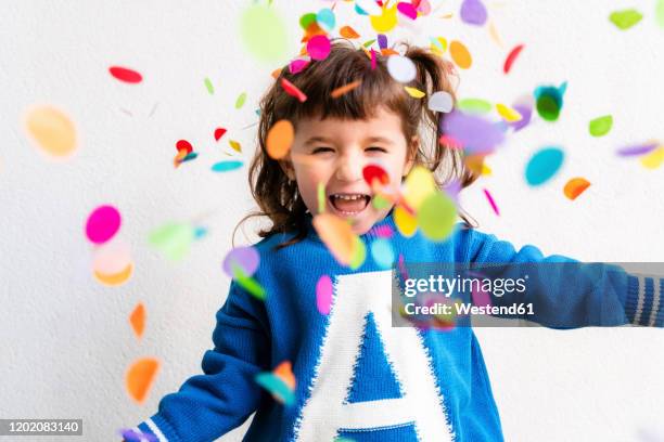 happy little girl blowing the confetti at a party in front of a white wall - 3 years brunette female alone caucasian stock pictures, royalty-free photos & images