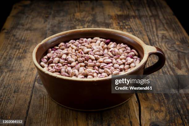 bowl of dried pinto beans lying on wooden table - borlotto bean stock pictures, royalty-free photos & images