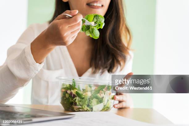 crop view of young architect eating mixed salad at desk - pranzo foto e immagini stock