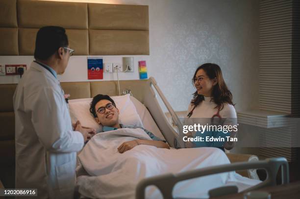 ein asiatischer chinesischer männlicher patient auf dem bett lächelnd erhielt gute nachrichten vom arzt über seine genesung - adult male hospital bed stock-fotos und bilder