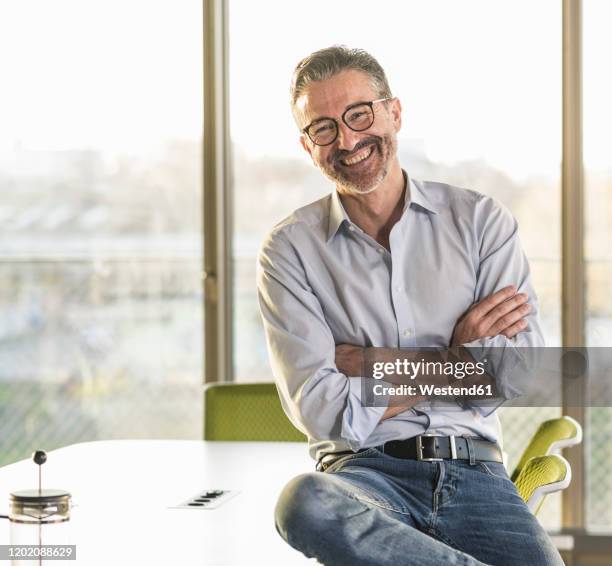 portrait of a happy mature businessman in office - gegenlicht stock-fotos und bilder