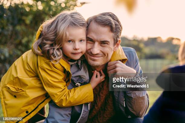 portrait of girl hugging smiling father outdoors in autumn - girl oilskin stock pictures, royalty-free photos & images
