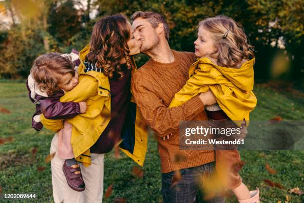 couple kissing outdoors in autumn watched by her daughters - girl oilskin stock pictures, royalty-free photos & images