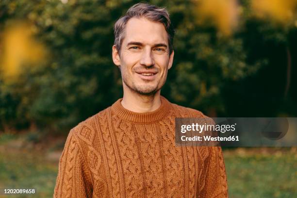 portrait of a smiling man outdoors in autumn - mann pullover stock-fotos und bilder