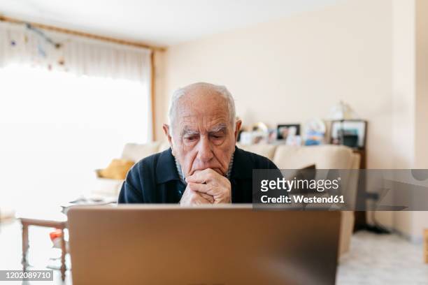 portrait of senior man using laptop at home - senior men computer stock pictures, royalty-free photos & images
