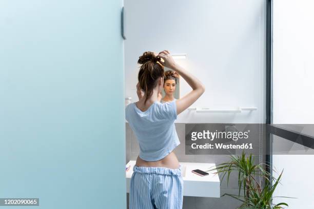 rear view of young woman in bath room - 鏡　女性 ストックフォトと画像