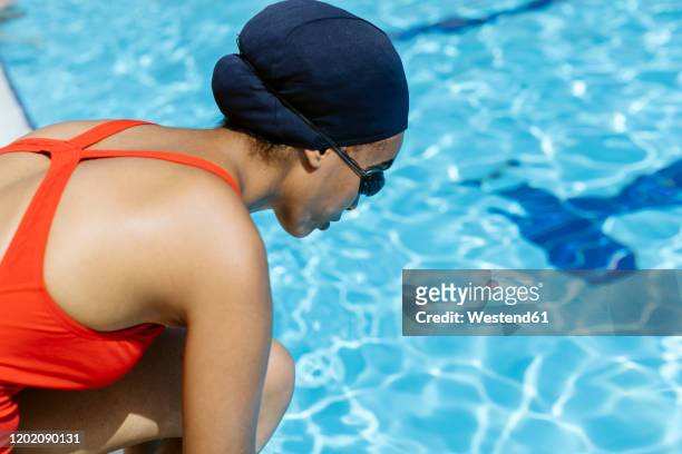 young woman wearing swimming cap and goggles at poolside - cuffia da nuoto foto e immagini stock