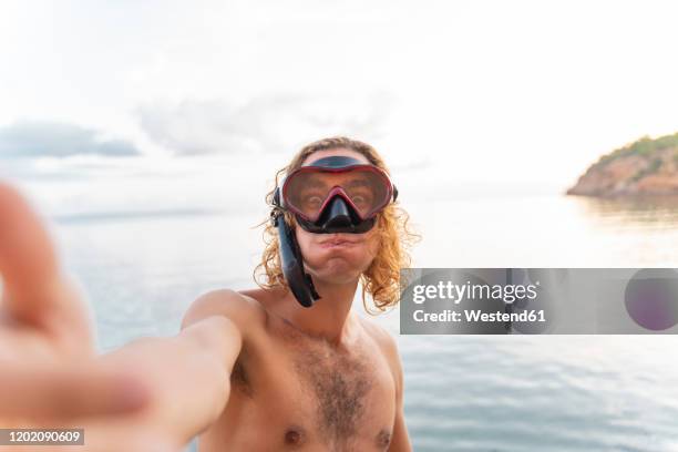 young man with snorkel making a face on the beach - scuba mask stock pictures, royalty-free photos & images