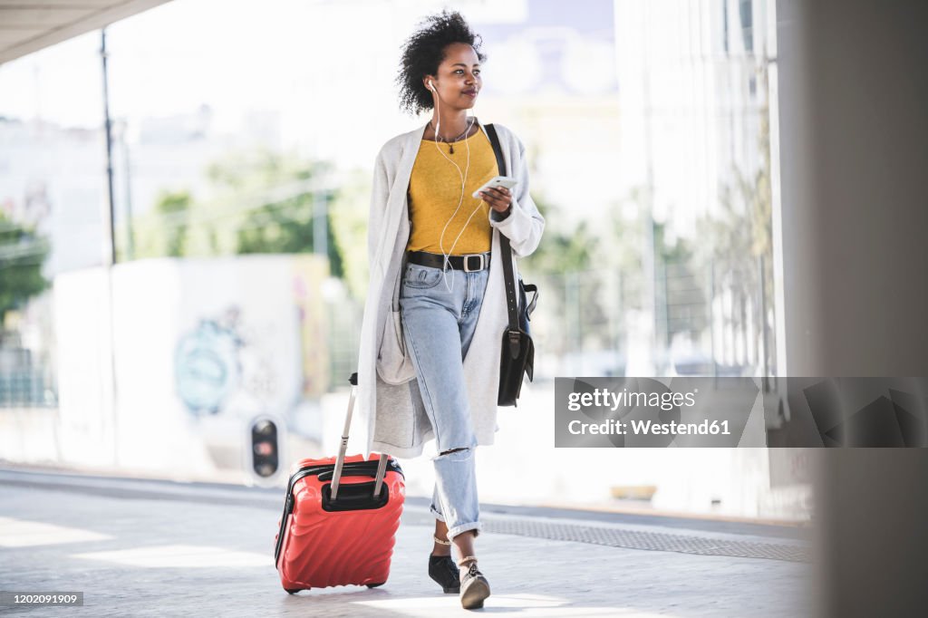 Young woman with cell phone and earphones at the train station