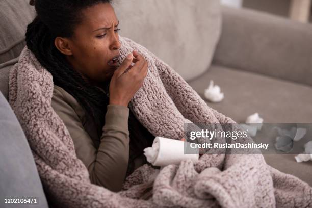 zieke vrouw die behandelende mond met de hand hoest, die op laag zit. - slijm stockfoto's en -beelden