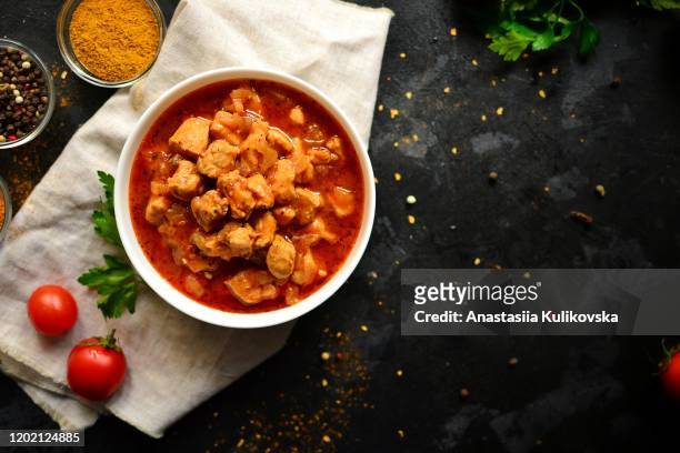 dish of indian cuisine tikka masala. chicken meat in tomato underpouring. tikka masala in a white pyalka on a dark background, a view from above, a place for text. dark background. linen napkin. - tikka masala stockfoto's en -beelden