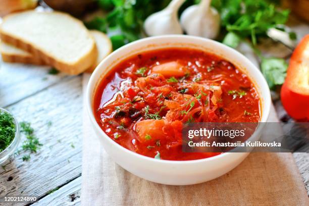 ukrainian and russian cuisine. red borscht. soup of tomatoes, cabbage and vegetables. borsch in a white pyalka on a wooden background. vegetarian food - borscht stockfoto's en -beelden