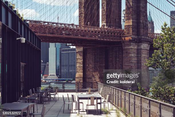 outdoor cafe in dumbo neighborhood with view of brooklyn bridge - brooklyn stock pictures, royalty-free photos & images