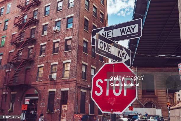 stop traffic sign and one way directions under brooklyn bridge in new york - one direction stock pictures, royalty-free photos & images