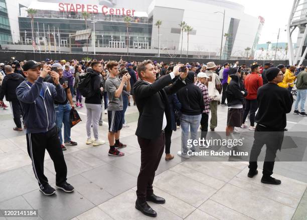 People take photos a screen as Former NBA player Kobe Bryant is remembered outside the 62nd Annual GRAMMY Awards at STAPLES Center on January 26,...