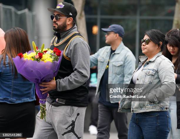 Man carries flowers as he mourns the death of retired NBA star Kobe Bryant outside the Staples Center prior to the 62nd Annual Grammy Awards on...