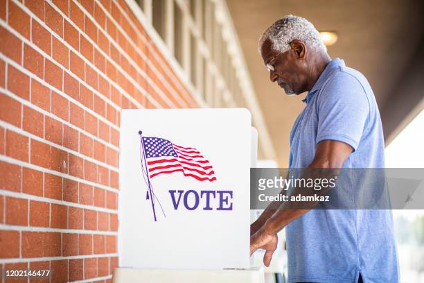 senior black man voting bij booth - presidentsverkiezing stockfoto's en -beelden